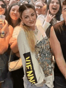a woman is standing in a crowd of people wearing a shirt that says wiennic on it .