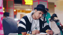 a man is sitting at a table writing in a notebook while eating a hamburger .