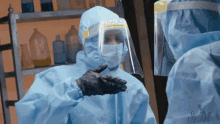 a person wearing a face shield and gloves is talking to another person