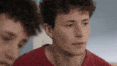 two young men with curly hair are looking at each other