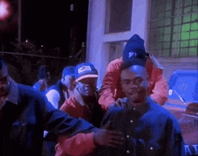 a group of men are standing around a man wearing a blue hat with the letter e on it .