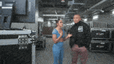 a man wearing a black jacket that says nocc on it talks to a woman