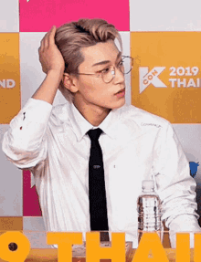 a man in a white shirt and tie holds his hand to his hair