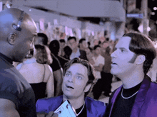 a man in a purple jacket is talking to a man in a black shirt