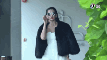 a woman wearing sunglasses and a fur coat with the number 3 on the bottom left