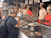 a man is standing at a counter in a restaurant eating a crepe .