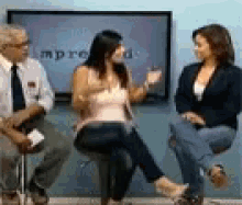a man and two women are sitting in front of a screen that says improu