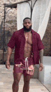 a shirtless man with a beard is wearing a maroon shirt and shorts that say holiday