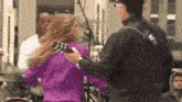 a woman in a purple sweater is holding a guitar