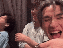 a group of young men are laughing together and one of them has his tongue out .
