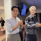 two men standing next to each other in a room