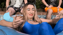 a woman in a blue leotard is laying in a pool with two men