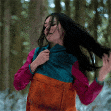 a woman in a colorful jacket is holding her hair