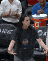 a woman in an at & t t-shirt stands in front of an orange gatorade bucket