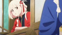 a girl in a red shirt looks out of a window