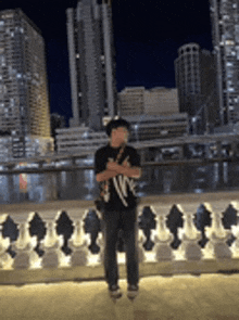 a man is standing on a balcony with a city in the background .