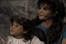 a woman and a little girl are standing next to each other and talking .
