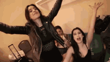 two women are standing next to each other with their arms in the air and screaming .