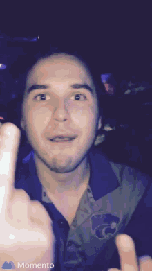 a man in a k-state shirt giving the middle finger