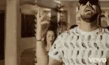 a man with a beard and sunglasses is dancing in a room with a woman .