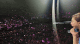 a woman singing into a microphone in front of a crowd of people