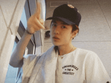 a young man wearing a hat and a white shirt that says fingerlocker on it
