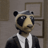 a cartoon bear wearing a suit and tie stands in front of a framed certificate that says college