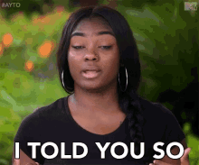 a woman is saying `` i told you so '' while standing in front of a green background .