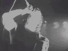 a black and white photo of a man standing in the dark with smoke coming out of his face .