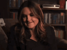 a woman is sitting on a couch in front of a bookshelf in a dark room .