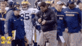 a group of michigan football players standing on the sidelines