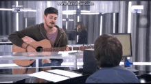 a man playing a guitar in front of a screen that says www.bandacam.com