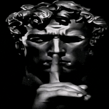 a black and white photo of a statue making a silence gesture