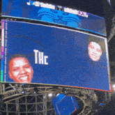 a large screen displays the word thc in white letters on a blue background