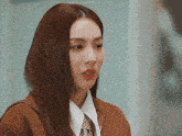 a woman with long hair is wearing a brown jacket and a white shirt and tie .
