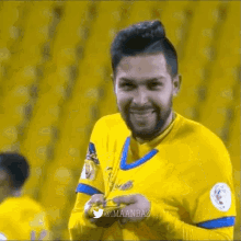 a man with a beard wearing a yellow and blue jersey is smiling