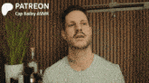 a man with a beard is standing in front of a sign that says patreon