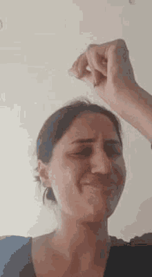 a woman is making a funny face while holding her hand to her head .