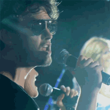 a man wearing sunglasses is singing into a microphone with the word reduce visible in the corner
