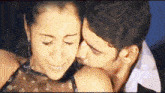 a man is kissing a woman on the cheek and the woman is smiling .