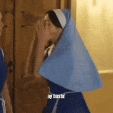 a woman in a nun costume is covering her face with her hand and says ay basta .