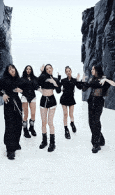 a group of women are dancing in front of a rock wall