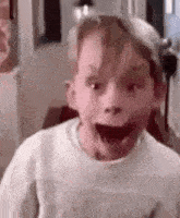 a young boy is making a funny face with his mouth open and his eyes closed .