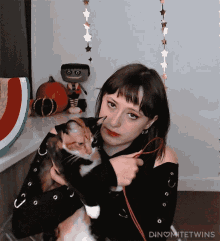 a woman holding a cat with the word dinomitetwins written on the bottom