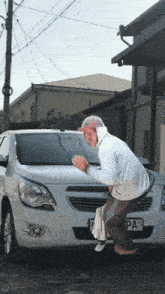 a man standing in front of a white car with a pa license plate