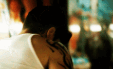 a man with a tattoo on his back looks down at something