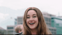a woman is smiling and looking at the camera in front of a city .