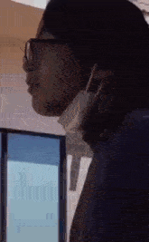 a woman wearing glasses and a face mask is standing in front of a window .