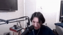 a woman is screaming into a microphone while sitting in front of a television .