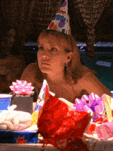 a woman wearing a birthday hat is sitting at a table